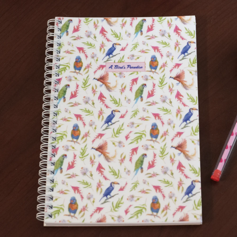 A Bird's Paradise planner cover with tropical parrots, toucans, and pink foliage watercolor pattern on wire-o bound notebook
