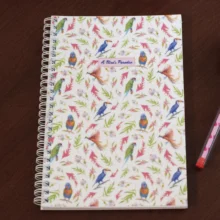 A Bird's Paradise planner cover with tropical parrots, toucans, and pink foliage watercolor pattern on wire-o bound notebook