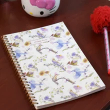 A Chirp Away illustrated planner cover showing watercolor birds, sunflowers, and botanical patterns on a wire-o bound notebook